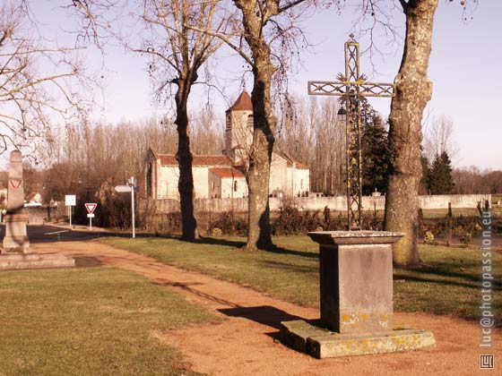 Une grande place ombrage, avec le monument aux mort et une croix assez rcente.